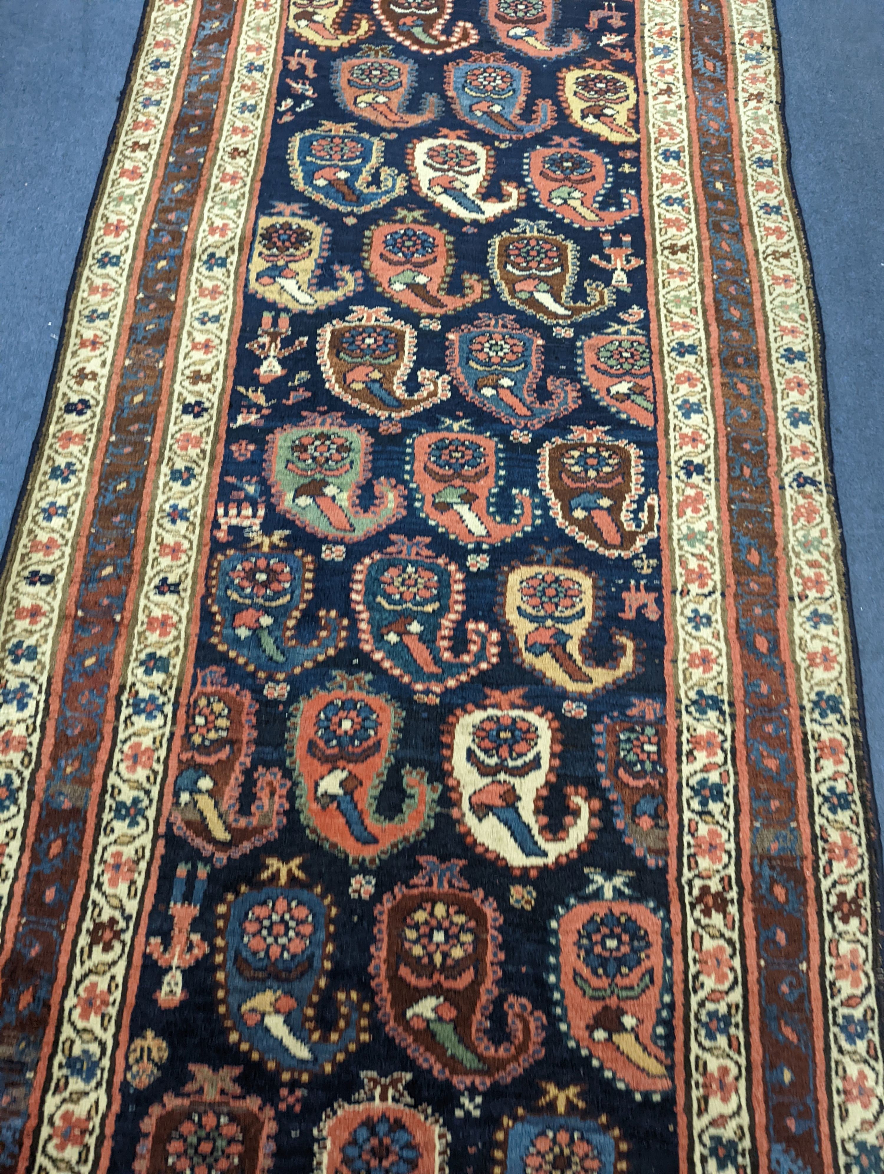 A Caucasian Karabagh blue ground runner, woven with rows of stylised boteh, figures and birds, 477 x 117cm